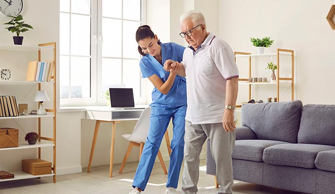 A female caregiver assisting an elderly man to stand up