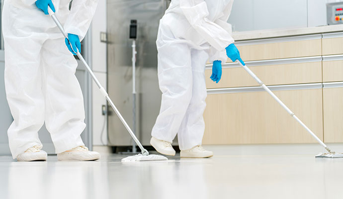 Biohazard cleanup team in protective suits sanitizing a floor