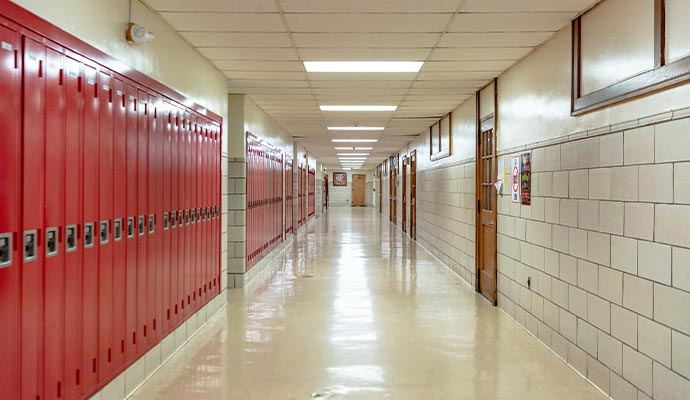 A long, clean school hallway with red lockers on the left