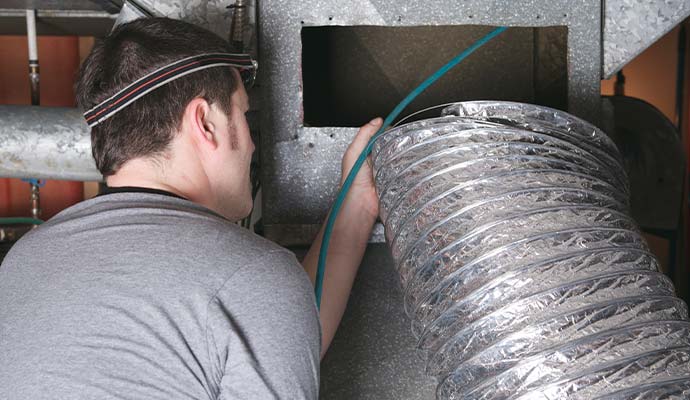 Technician cleaning air duct for smoke removal