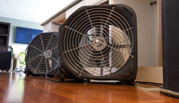 Industrial air movers drying hardwood floor