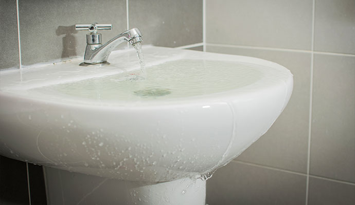 Tiled bathroom sink overflowing with water